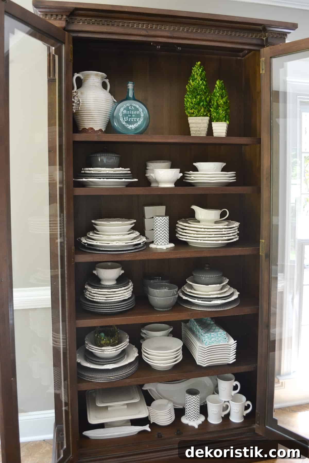 Stunning Kitchen Remodel: Before and After Reveal 14 tall wood cabinet with glass doors filled with white plates, platters and bowls