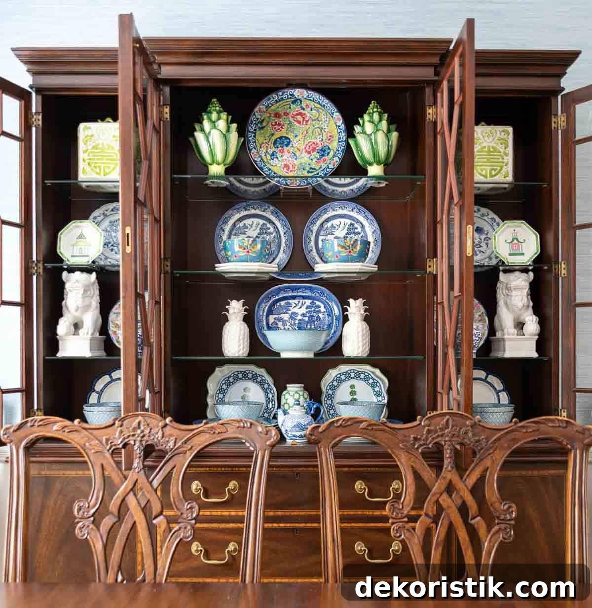 Traditional dining room with blue grasscloth walls, antique wood dining table and chairs, blue and white china, brass chandelier, and colorful chinoiserie accents.