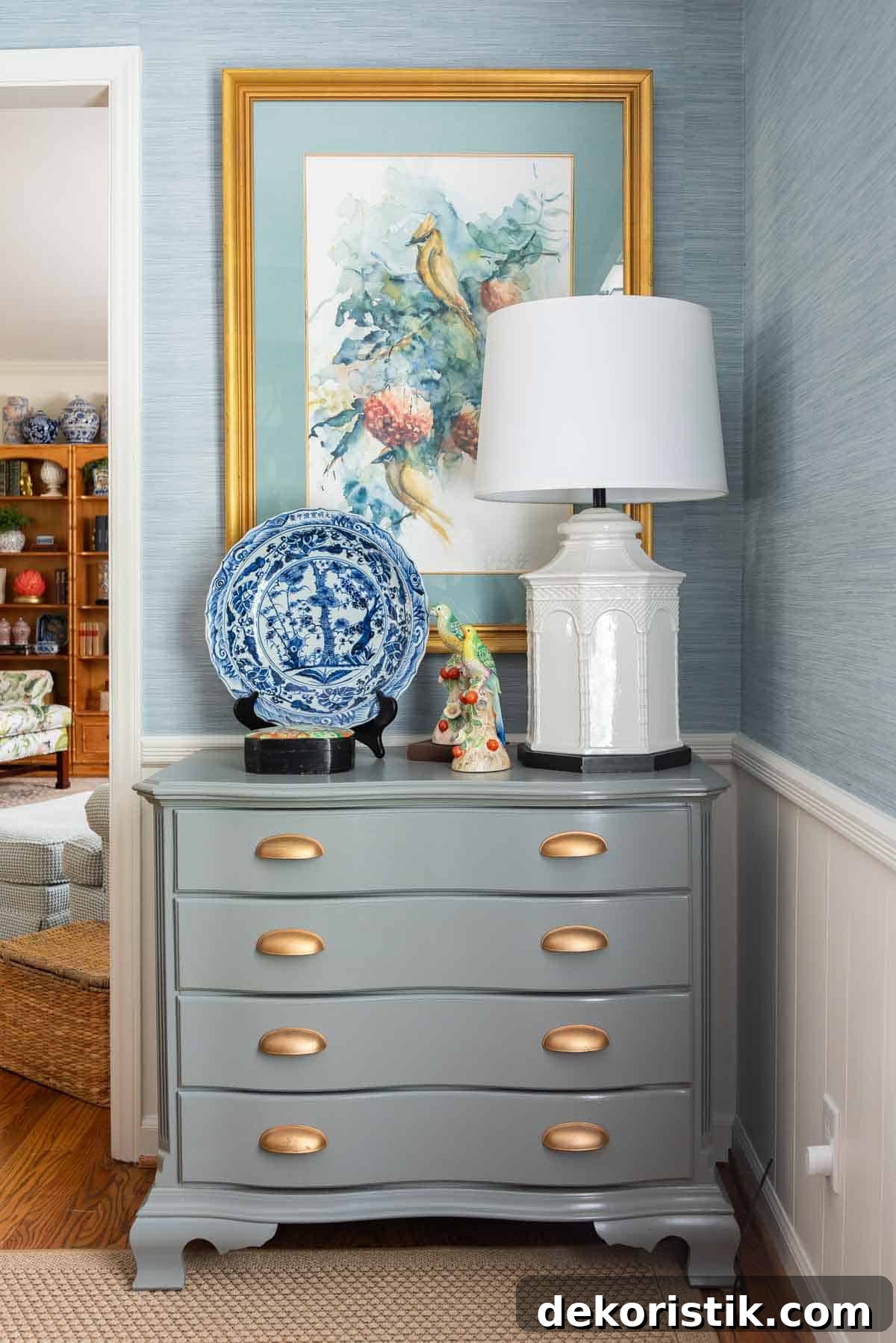 Traditional dining room with blue grasscloth walls, antique wood dining table and chairs, blue and white china, brass chandelier, and colorful chinoiserie accents.